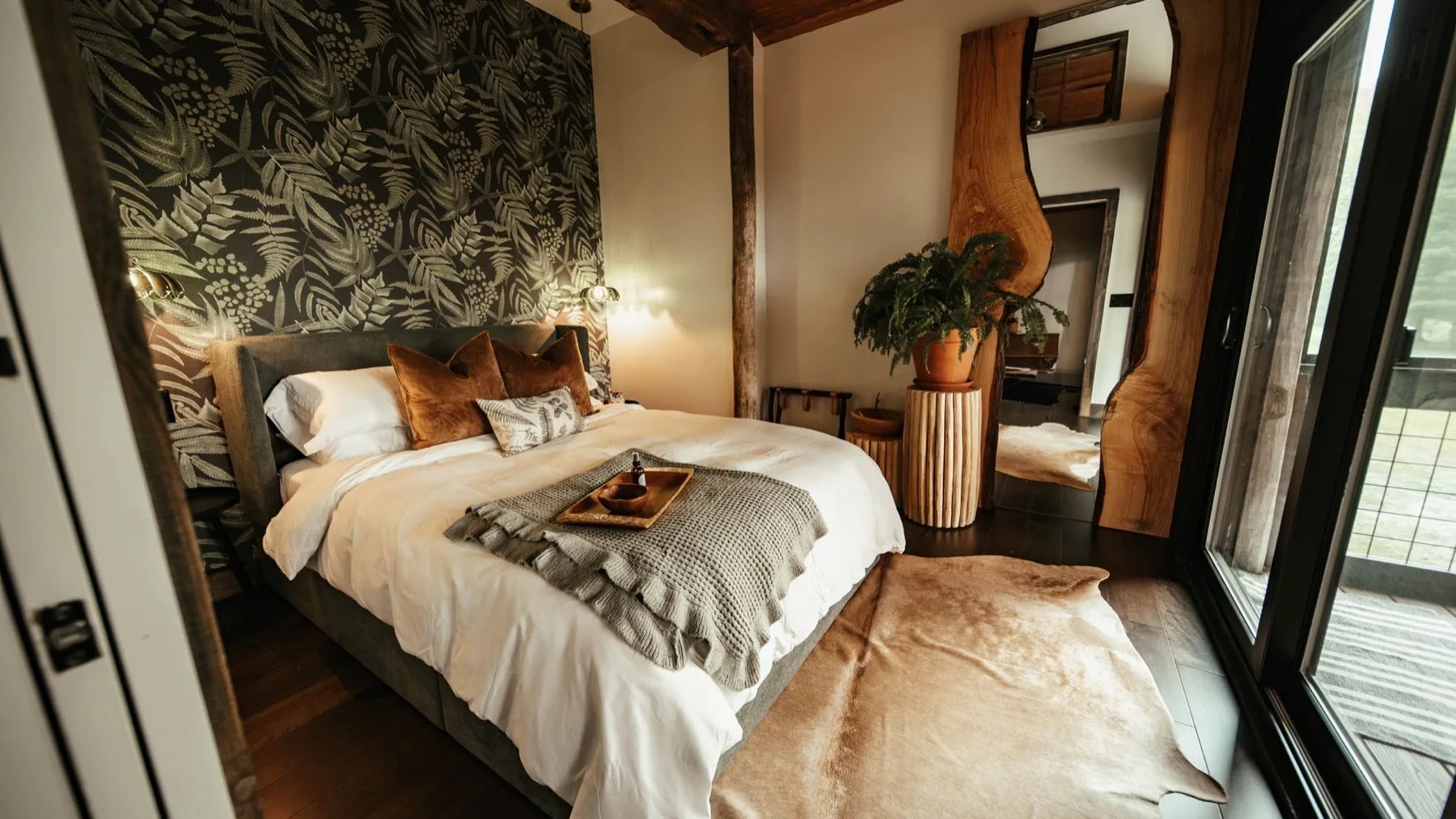 Second bedroom with dark botanical wallpaper, an upholstered headboard and a sliding glass door out to the deck