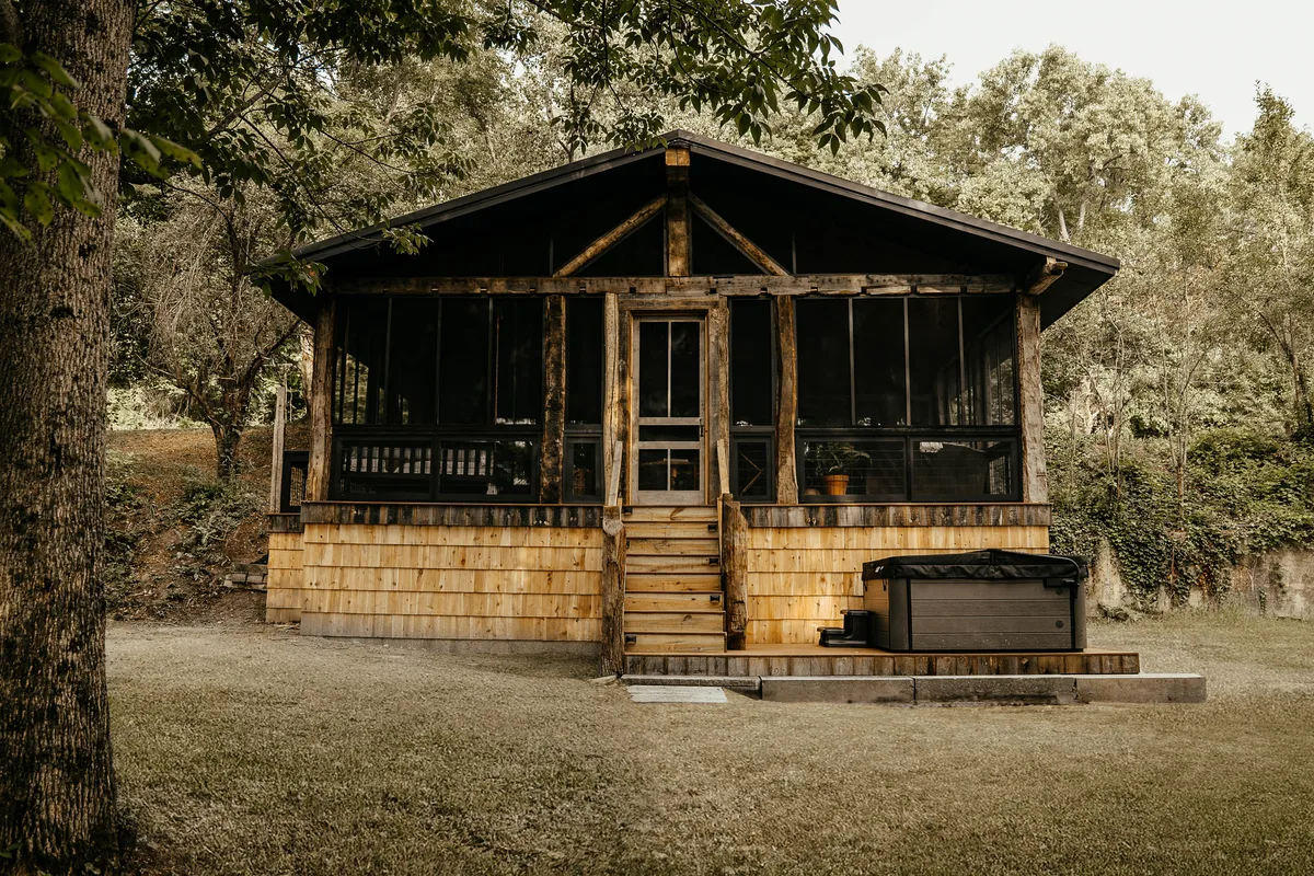 The 19A Cabin from the lawn, cedar shingle with a black-roofed screened porch under the trees