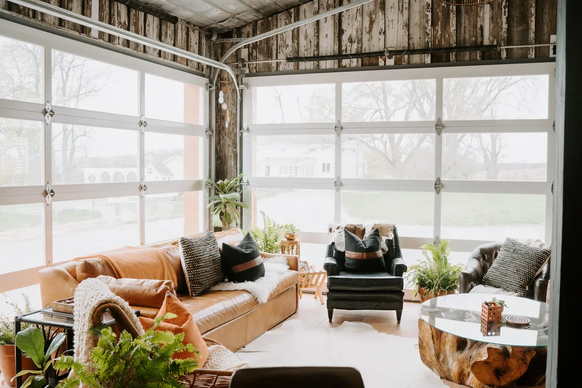 Southview with its glass wall rolled open onto farmland and a pond, a camel leather sofa inside