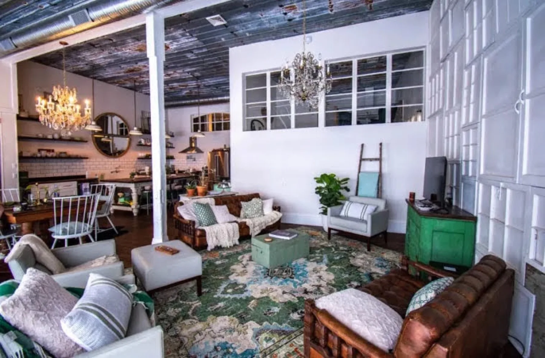 A second sitting area with vintage tufted chesterfield sofas, a patterned rug, a green cabinet and a round mirror