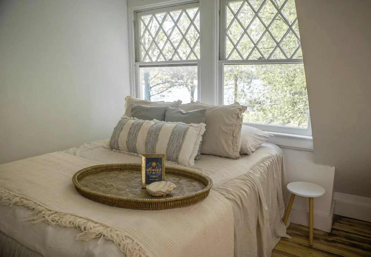 King bedroom with cream linens and a bank of windows over the lake