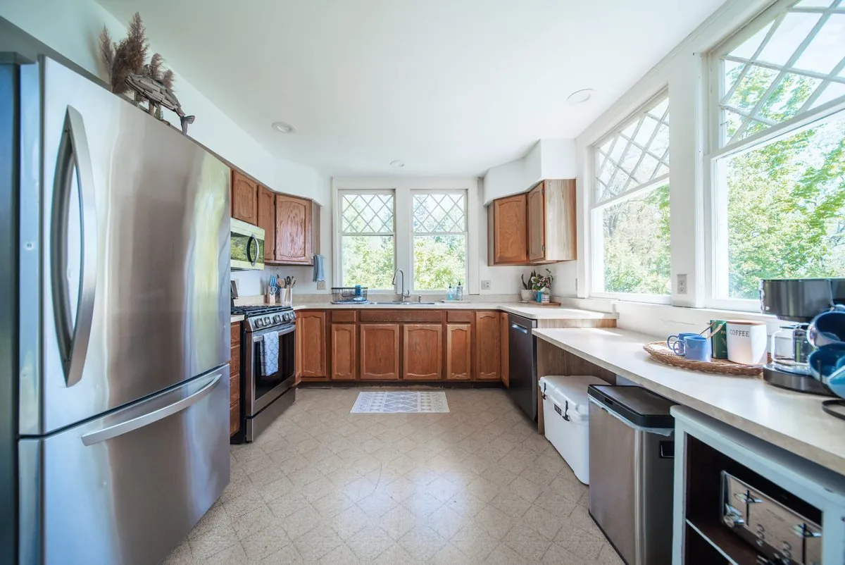 The lake house kitchen with honey oak cabinets, a stainless range and diamond-leaded windows above the sink