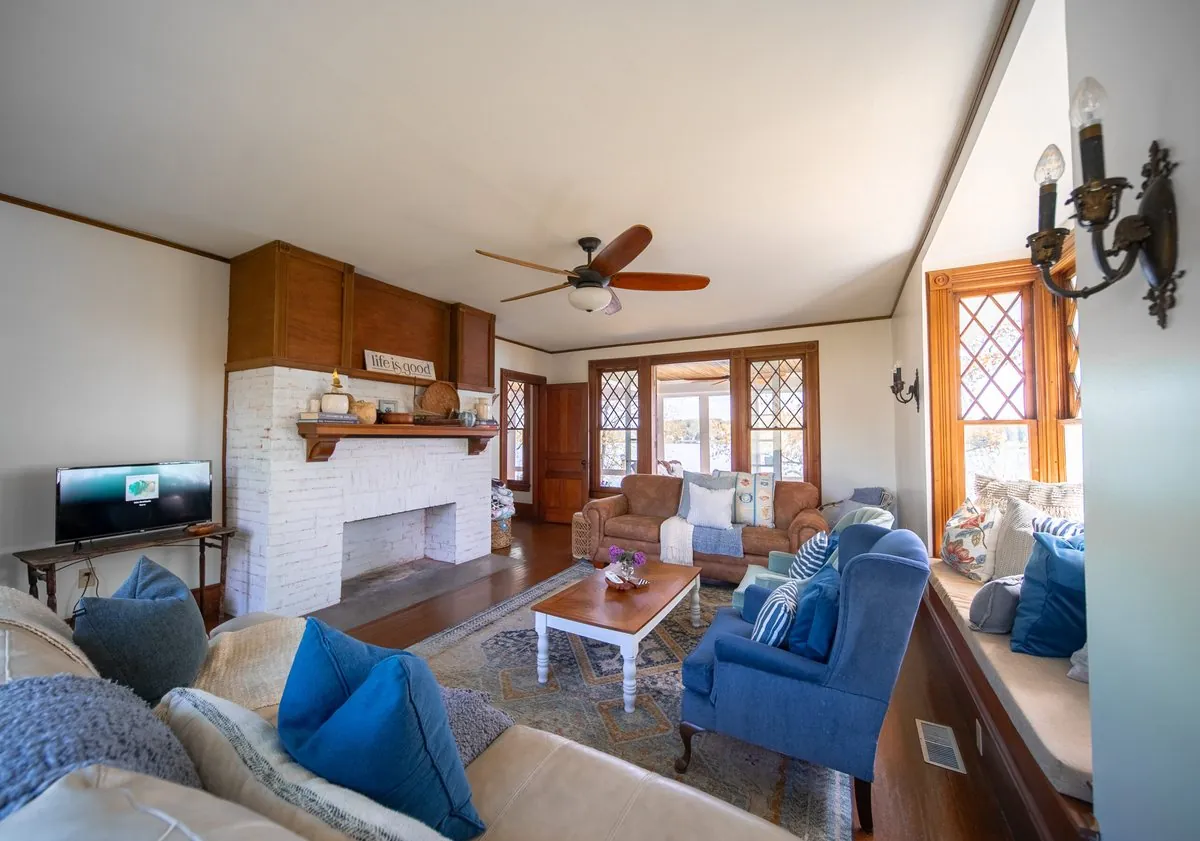 Living room with a white brick fireplace, blue sofas and leaded windows