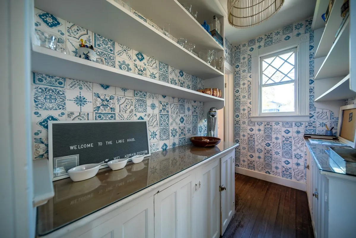 Butler pantry with blue and white patterned wallpaper and open shelving