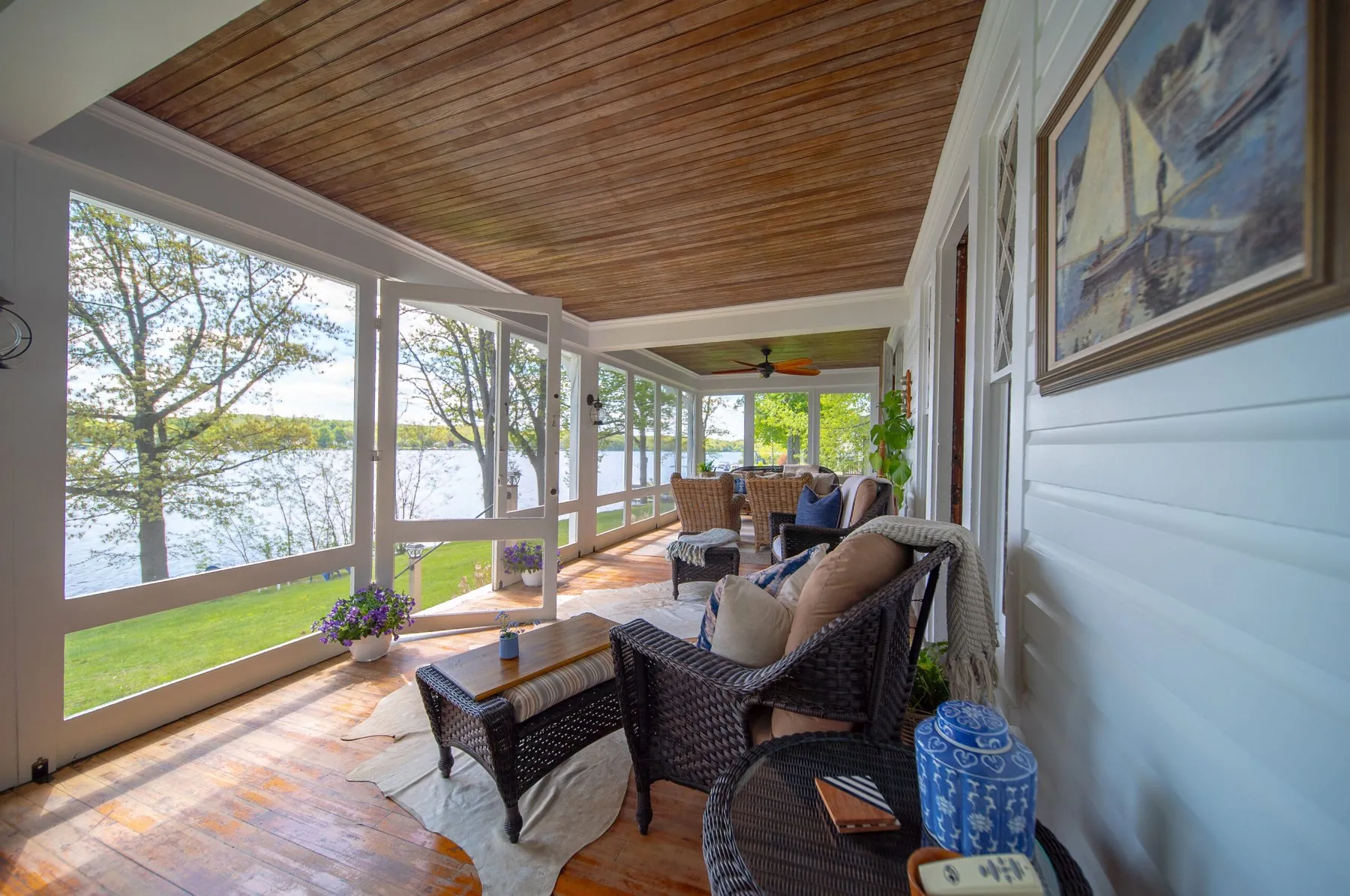 The large screened porch at Silver Lake Haus with wicker seating and a dining table looking out over the water
