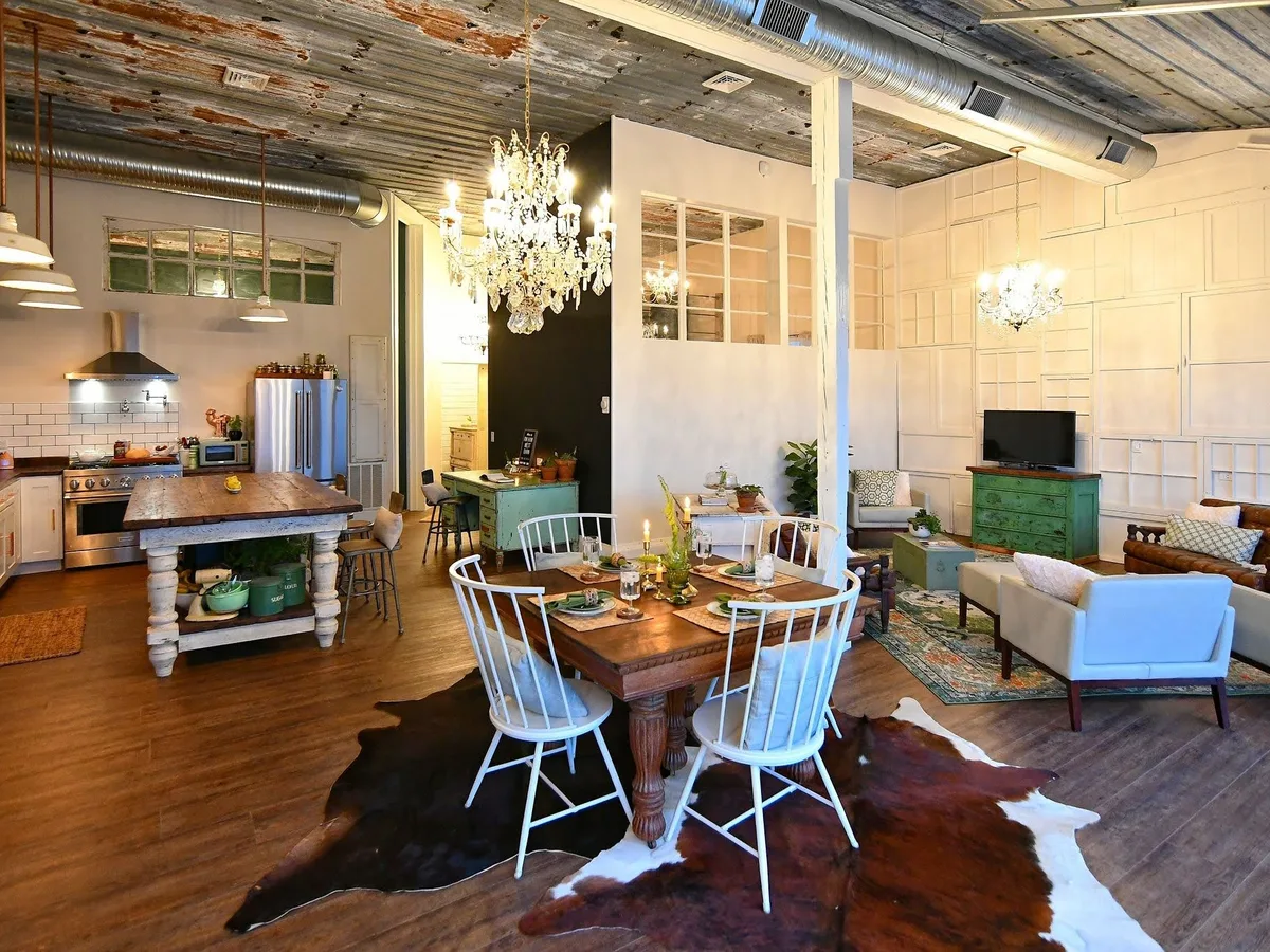 The Highbanks great room, rusted tin ceiling, chandeliers over a farm table and cowhide rugs