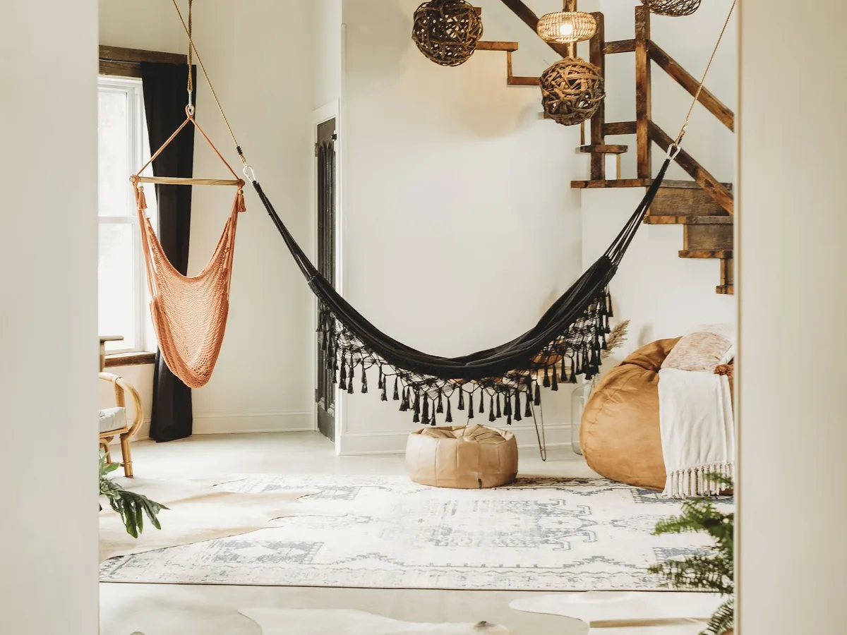 The Southview great room with two hanging swing chairs beside the staircase under woven pendants