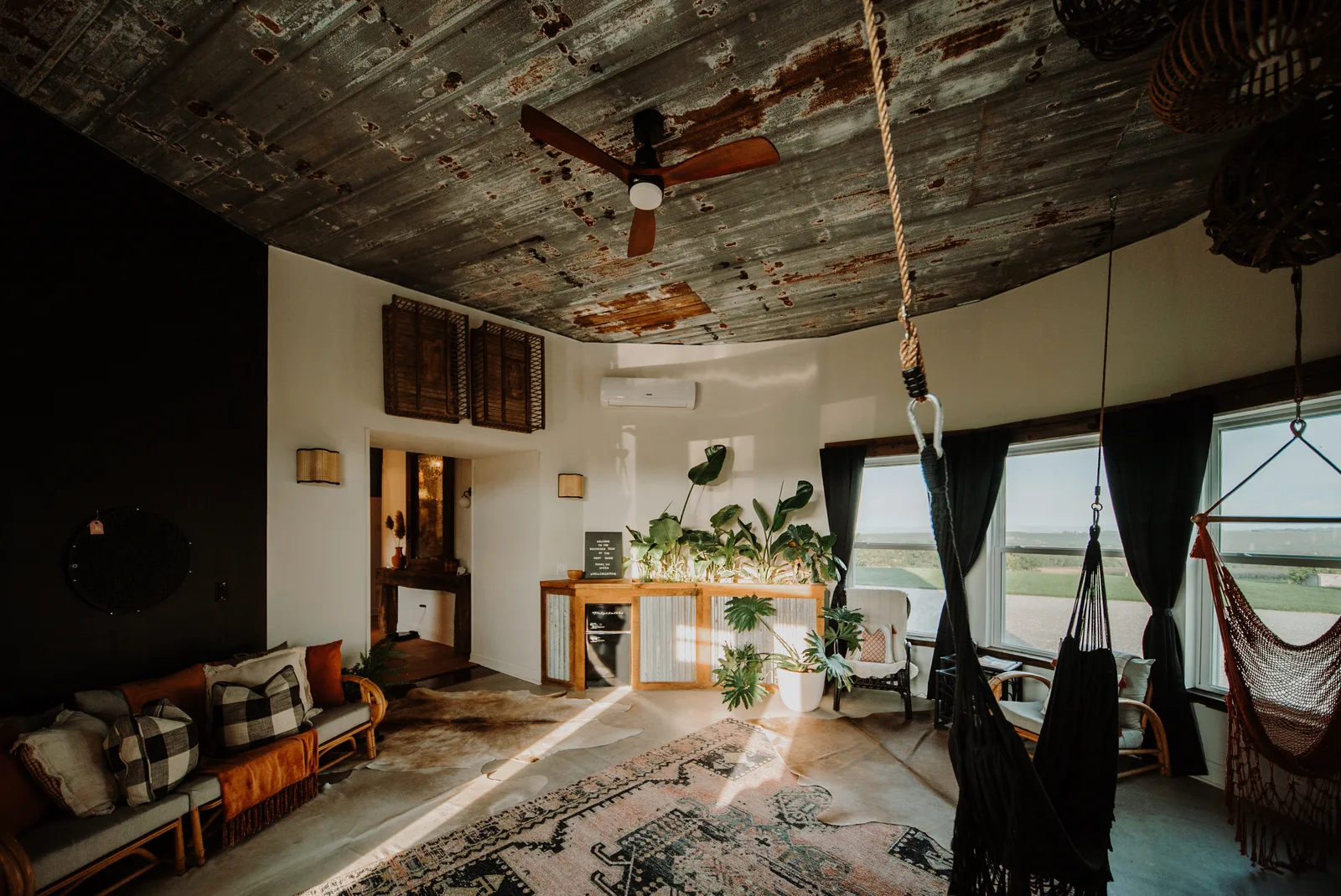Southview living room with indoor hammocks, a weathered tin ceiling and corner pasture views