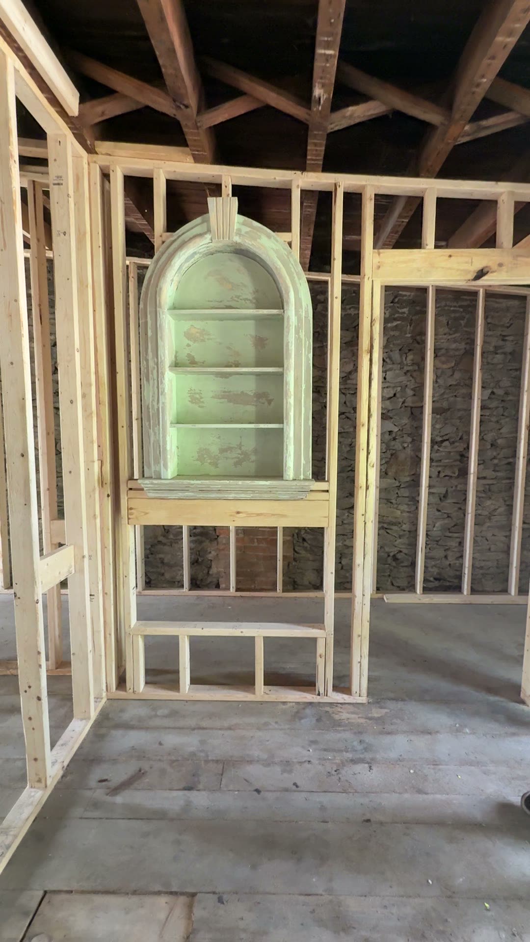New wood framing going up around an old arched built-in niche