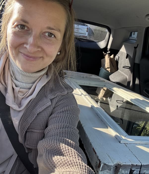 Amanda in her car with old window frames loaded in the back